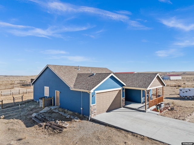 ranch-style home featuring a garage, concrete driveway, stone siding, roof with shingles, and fence