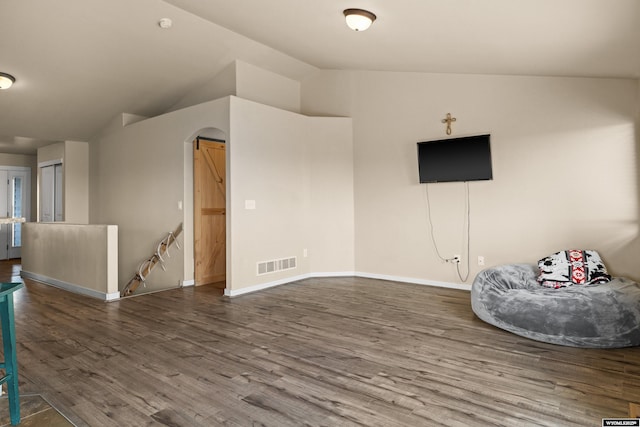 unfurnished room featuring arched walkways, lofted ceiling, visible vents, an upstairs landing, and wood finished floors