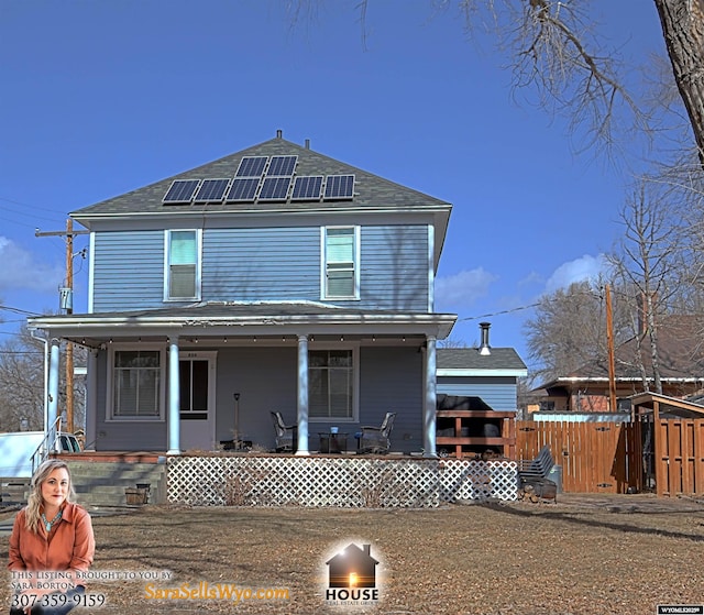 view of front facade with a porch, fence, and solar panels