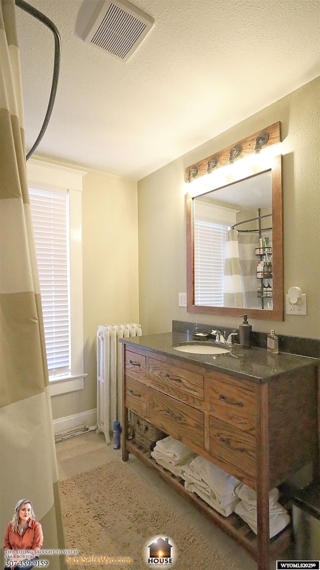 full bath with a textured ceiling, a shower with shower curtain, vanity, visible vents, and radiator heating unit