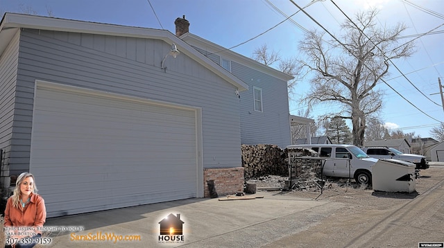 view of home's exterior with a garage, concrete driveway, and a chimney