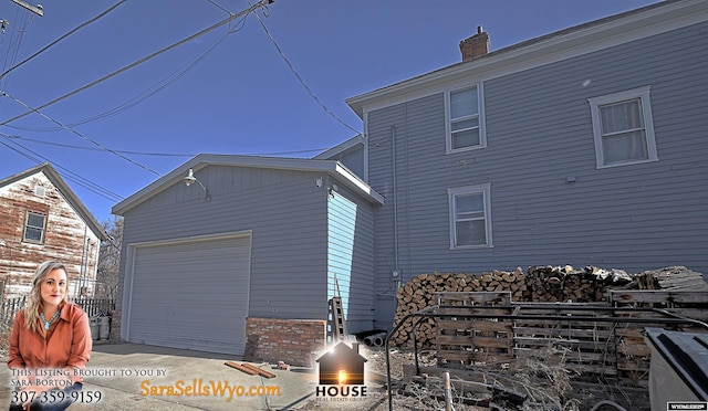 view of side of home with a garage, a chimney, and an outbuilding