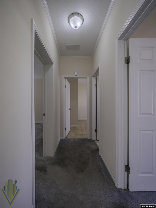 hallway featuring carpet floors, visible vents, and crown molding