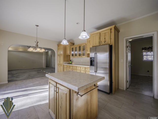 kitchen with arched walkways, light countertops, hanging light fixtures, glass insert cabinets, and stainless steel fridge with ice dispenser