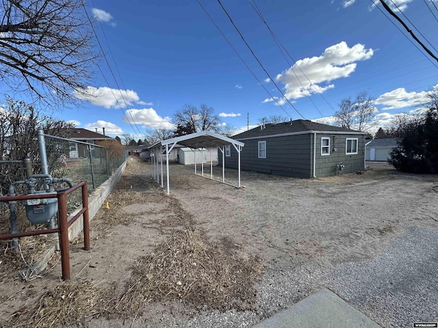 view of home's exterior featuring a detached carport, fence, and driveway