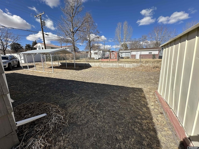 view of yard featuring a detached carport, a playground, and fence