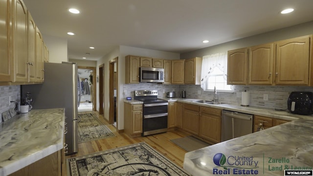 1596 Rd 109, Cheyenne, WY 82009 - kitchen with stainless steel appliances, light wood-type flooring, a sink, and backsplash