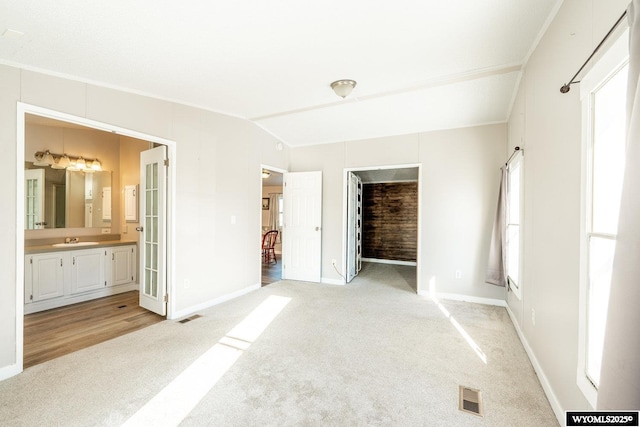 unfurnished bedroom with light carpet, vaulted ceiling, a sink, and visible vents