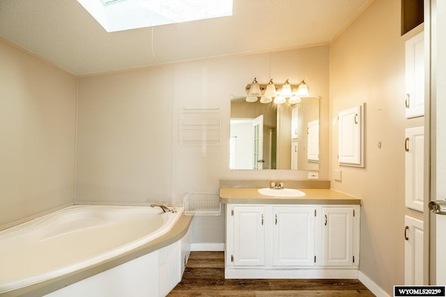 bathroom featuring a skylight, baseboards, wood finished floors, a garden tub, and vanity