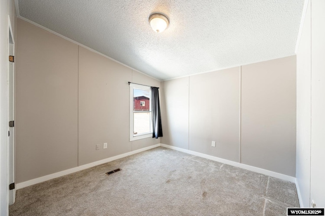 spare room with visible vents, lofted ceiling, ornamental molding, carpet, and a textured ceiling