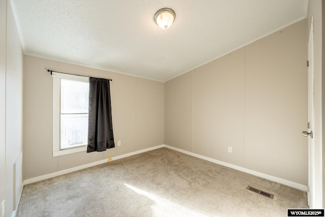 carpeted empty room featuring a textured ceiling and visible vents