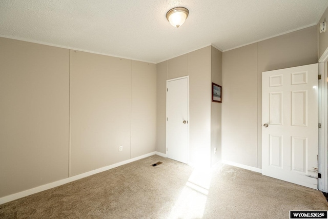 unfurnished bedroom with a textured ceiling, ornamental molding, carpet, and visible vents