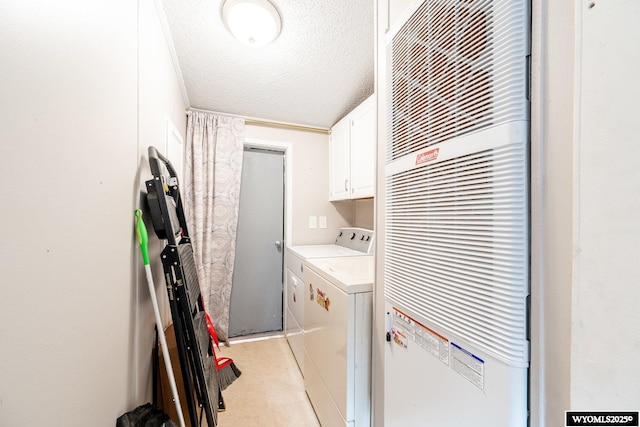 washroom featuring a textured ceiling, washer and clothes dryer, a heating unit, and cabinet space