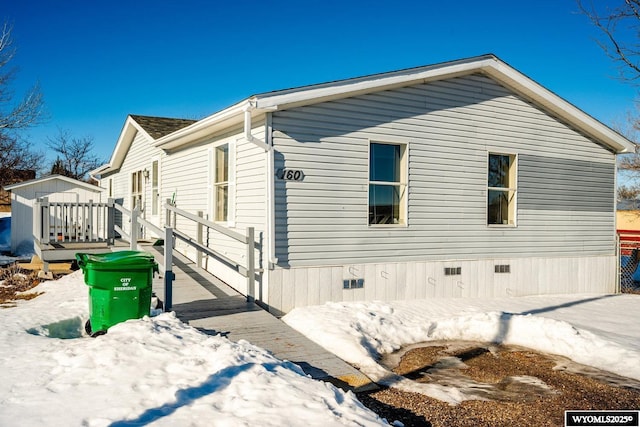 view of snow covered exterior with crawl space and a wooden deck