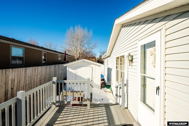 wooden deck with a shed, fence, and an outdoor structure