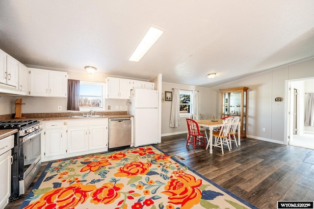 kitchen with dark wood-style flooring, stainless steel appliances, white cabinetry, a sink, and vaulted ceiling