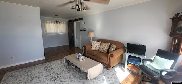 living area with a barn door, baseboards, wood finished floors, and ornamental molding