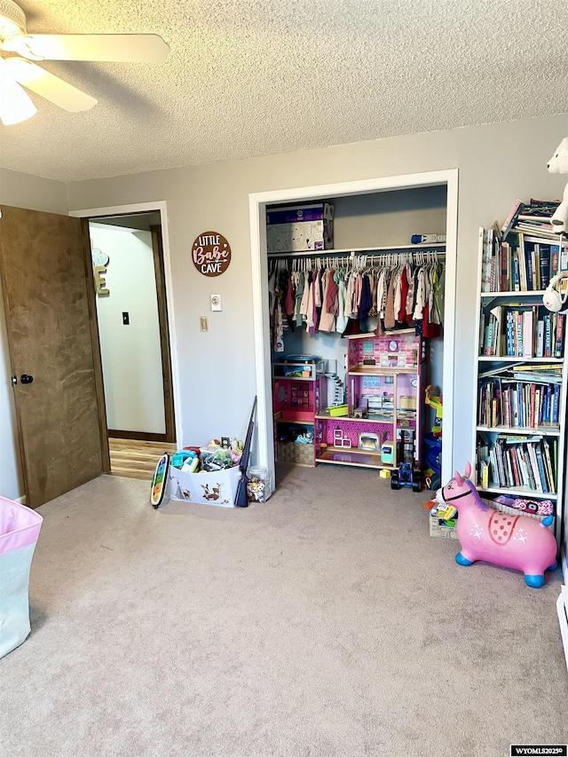 game room with carpet floors, ceiling fan, and a textured ceiling