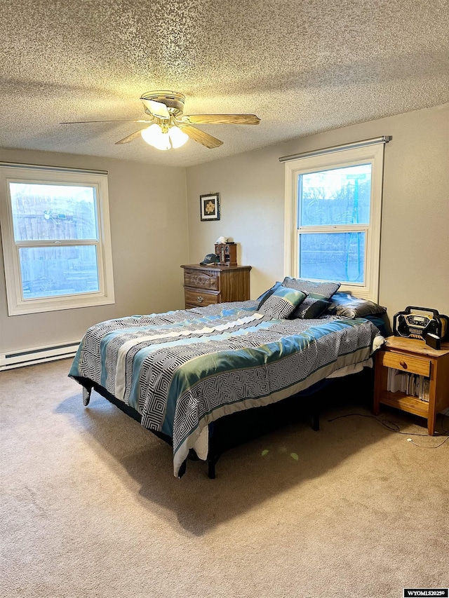 carpeted bedroom with a baseboard heating unit, multiple windows, ceiling fan, and a textured ceiling