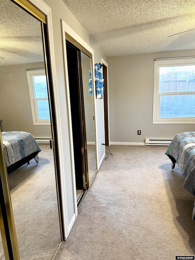 carpeted bedroom featuring a baseboard heating unit, a textured ceiling, a baseboard radiator, and baseboards