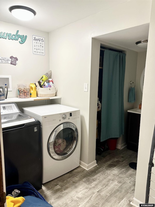 clothes washing area featuring light wood finished floors, baseboards, laundry area, and washer and clothes dryer