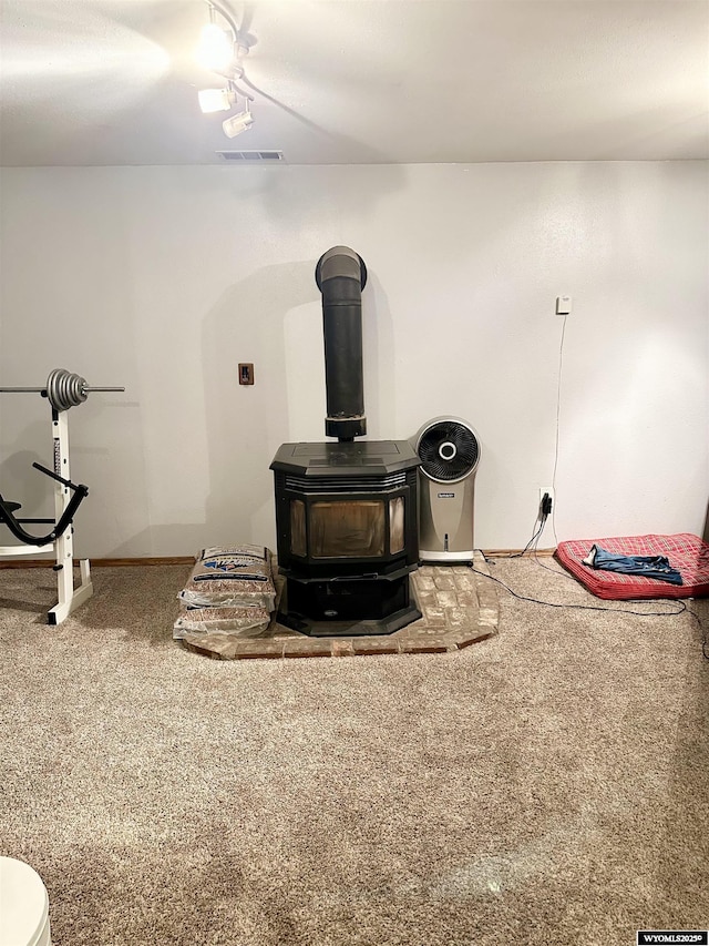 room details with carpet floors, a wood stove, visible vents, and baseboards