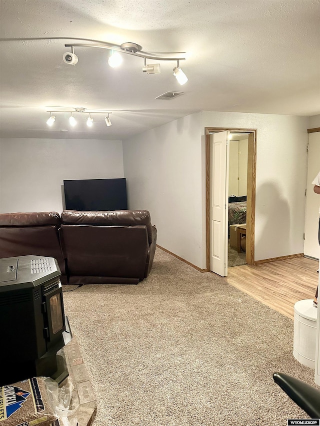 living room with a wood stove, baseboards, visible vents, and a textured ceiling