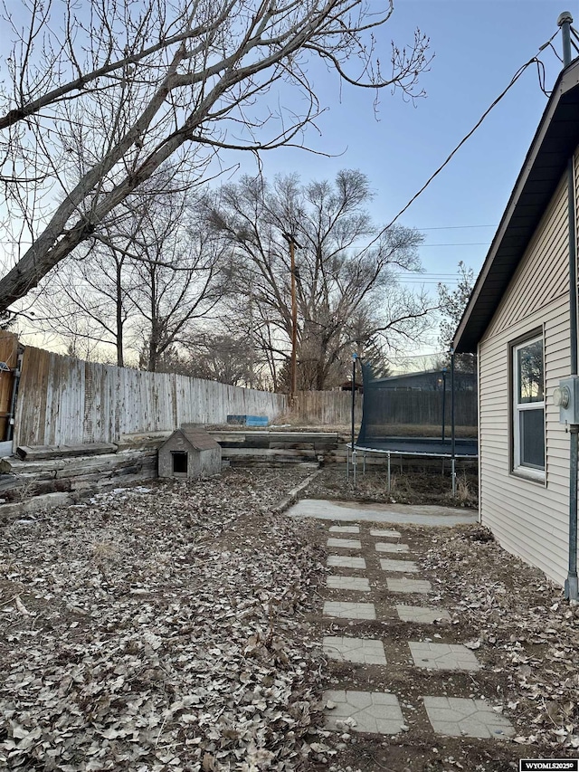 view of yard with a trampoline and fence