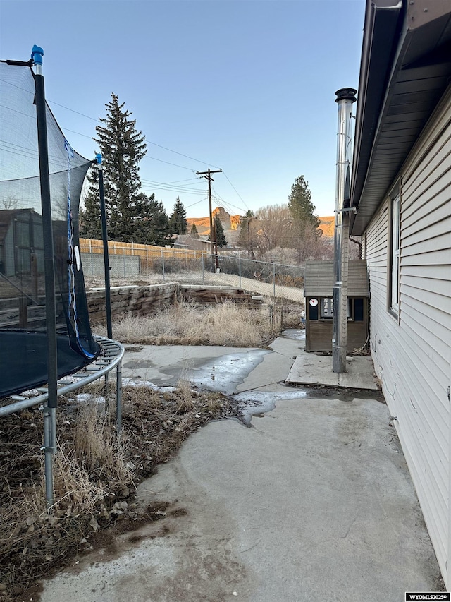 view of yard with a trampoline, a fenced backyard, and a patio