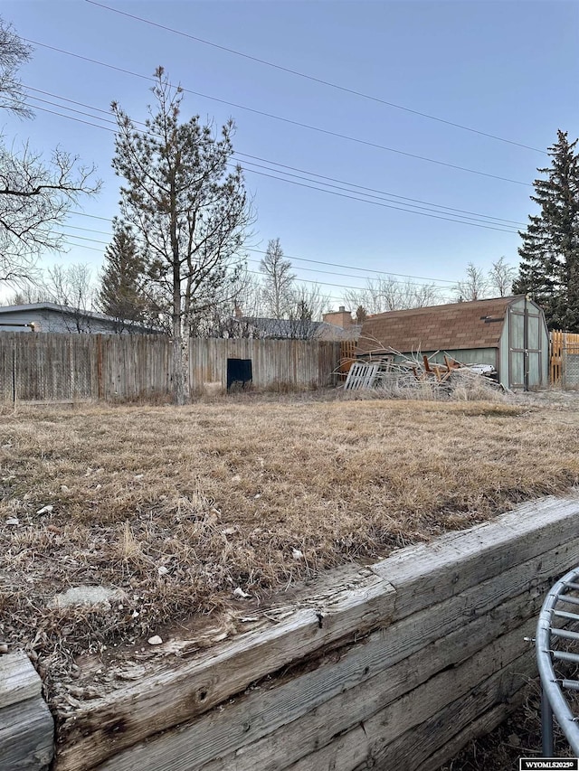 view of yard with a shed, fence, and an outbuilding