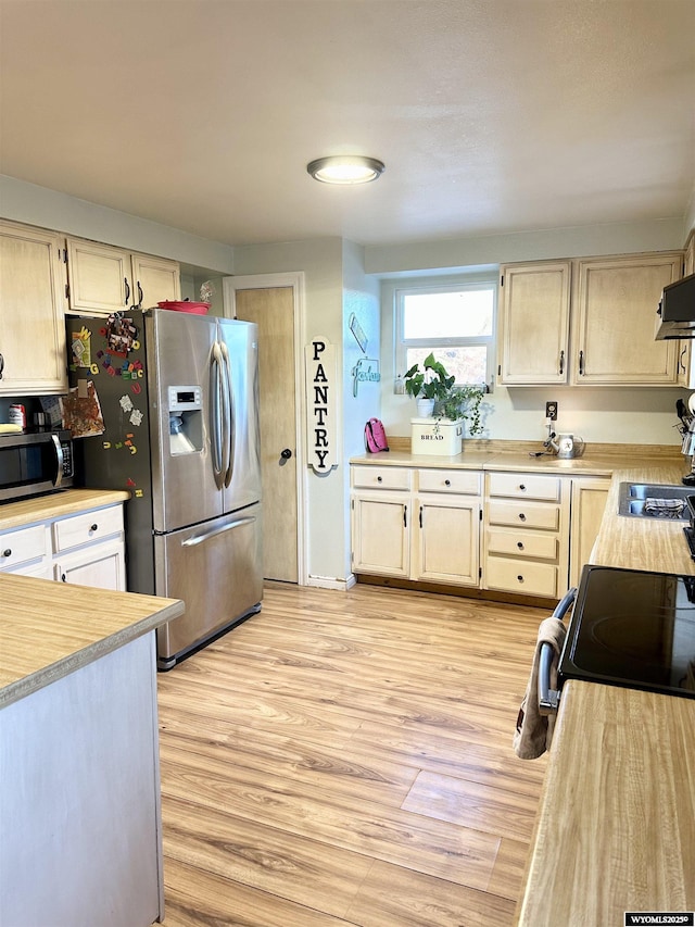 kitchen with stainless steel appliances, light wood-type flooring, light countertops, and exhaust hood