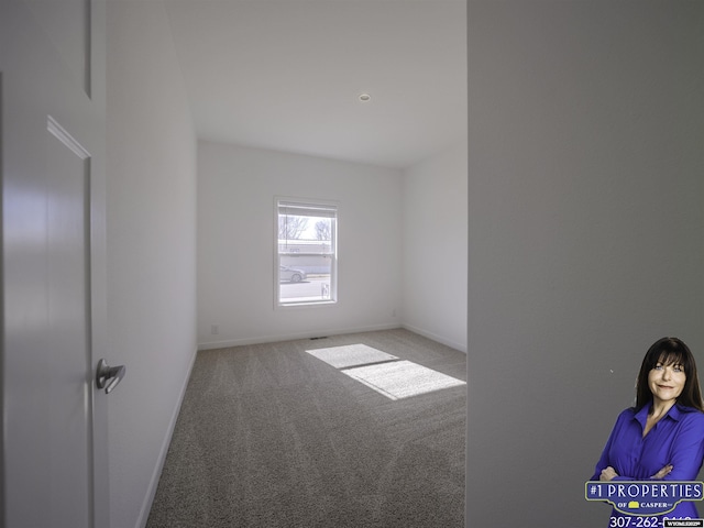 carpeted spare room featuring baseboards