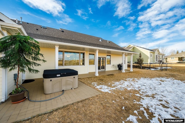 rear view of house featuring a shingled roof, a patio area, and a hot tub