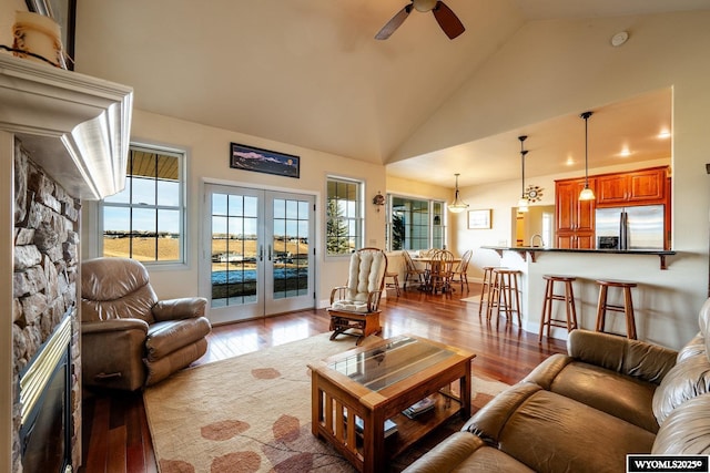 living room featuring french doors, a fireplace, light wood-style floors, ceiling fan, and high vaulted ceiling