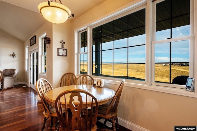 dining room with baseboards, vaulted ceiling, and wood finished floors