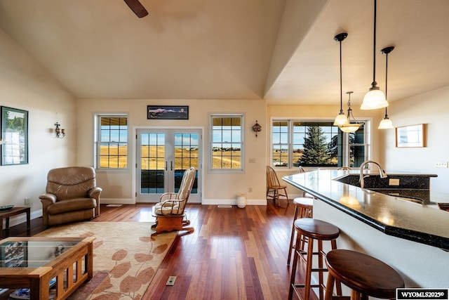 interior space featuring lofted ceiling, a breakfast bar area, dark wood-type flooring, french doors, and pendant lighting