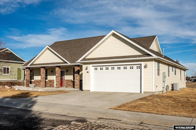 view of front facade with a shingled roof, concrete driveway, covered porch, an attached garage, and central AC