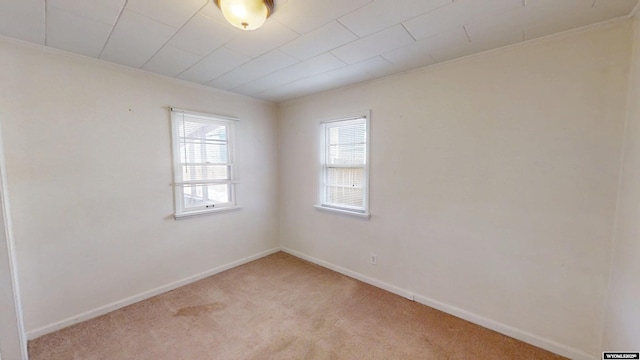 empty room featuring light carpet and baseboards