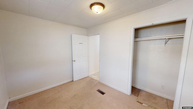 unfurnished bedroom featuring carpet, a closet, visible vents, and baseboards