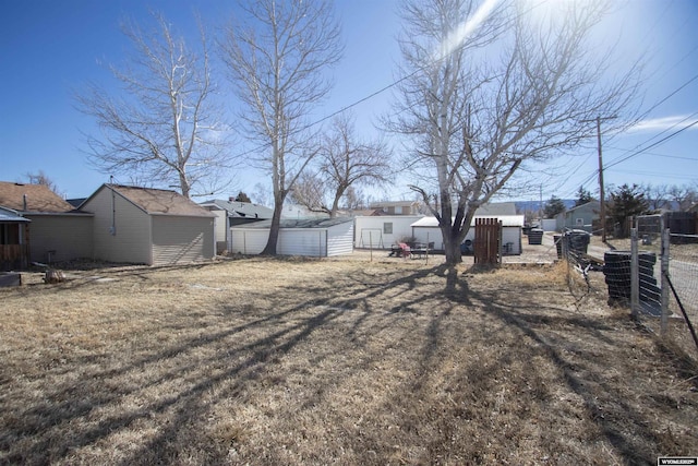 view of yard with a storage shed, an outdoor structure, and fence