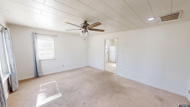 empty room featuring carpet floors, visible vents, baseboards, and a ceiling fan