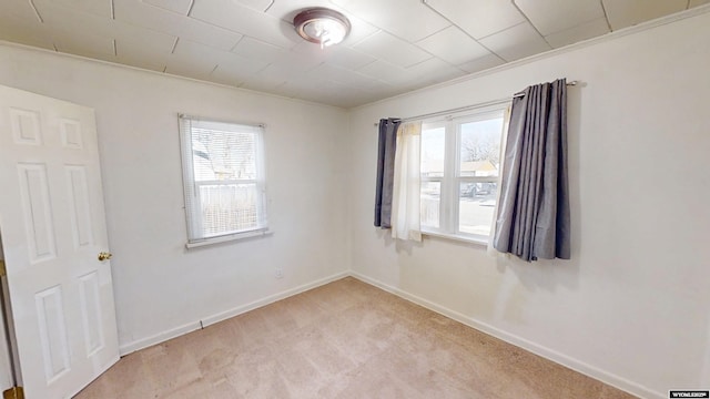 spare room with light carpet and baseboards