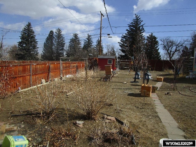 view of yard with a fenced backyard, an outdoor structure, and a storage unit