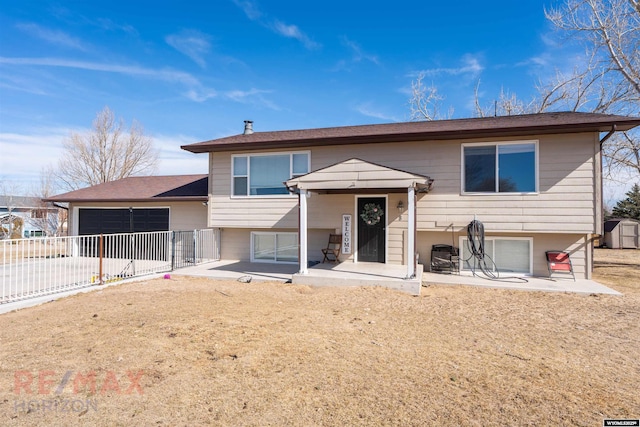 bi-level home featuring an attached garage, driveway, a patio area, and fence