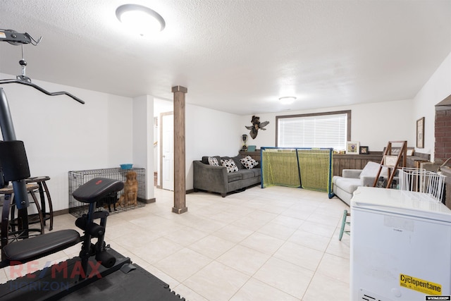 interior space featuring a textured ceiling, light tile patterned floors, and decorative columns