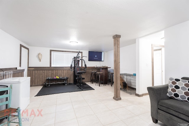 exercise room featuring wainscoting, wooden walls, and a dry bar