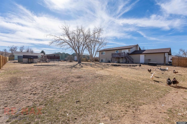 back of property featuring an outbuilding, a deck, fence, stairs, and a storage unit