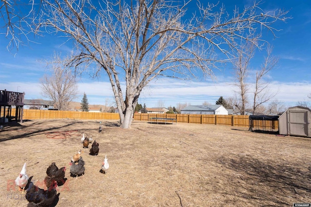 view of yard with a storage shed, a fenced backyard, and an outbuilding