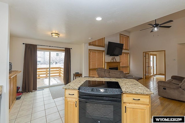 kitchen with open floor plan, light brown cabinets, ceiling fan, and black / electric stove