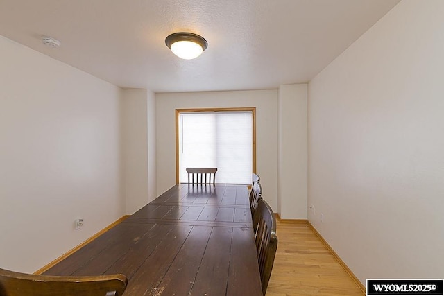 corridor featuring light wood-type flooring and baseboards